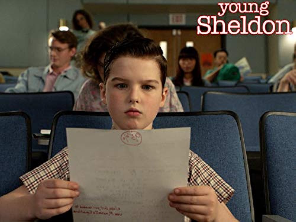 This is Young Sheldon in high school looking at his paper and the background shows the older students. Sheldon did got bullied because he was young and smart.