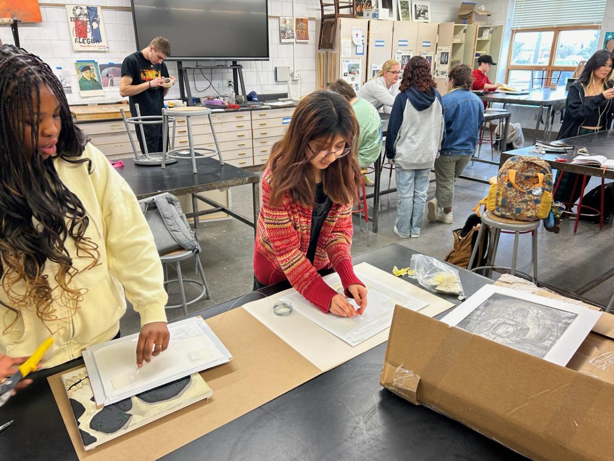 Senior Esmeralda Palma-Andrade  prepares for her next art competition in White Bear Lake; she attaches wire to the back of her painting so it can hang in a gallery. Palma-Andrade is being mentored by another student in her art class after she asked for help, the whole class works together to help one another. 