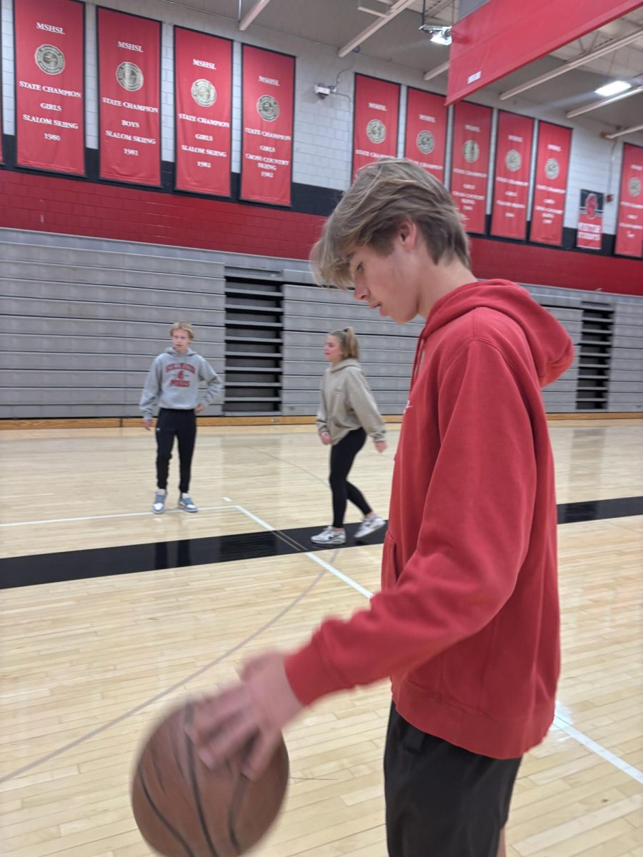 Lewis Hamilton dribbles the basketball waiting for his turn to shoot. He hopped around on a couple different courts and played without a lot of different students making lots of people happy. 
