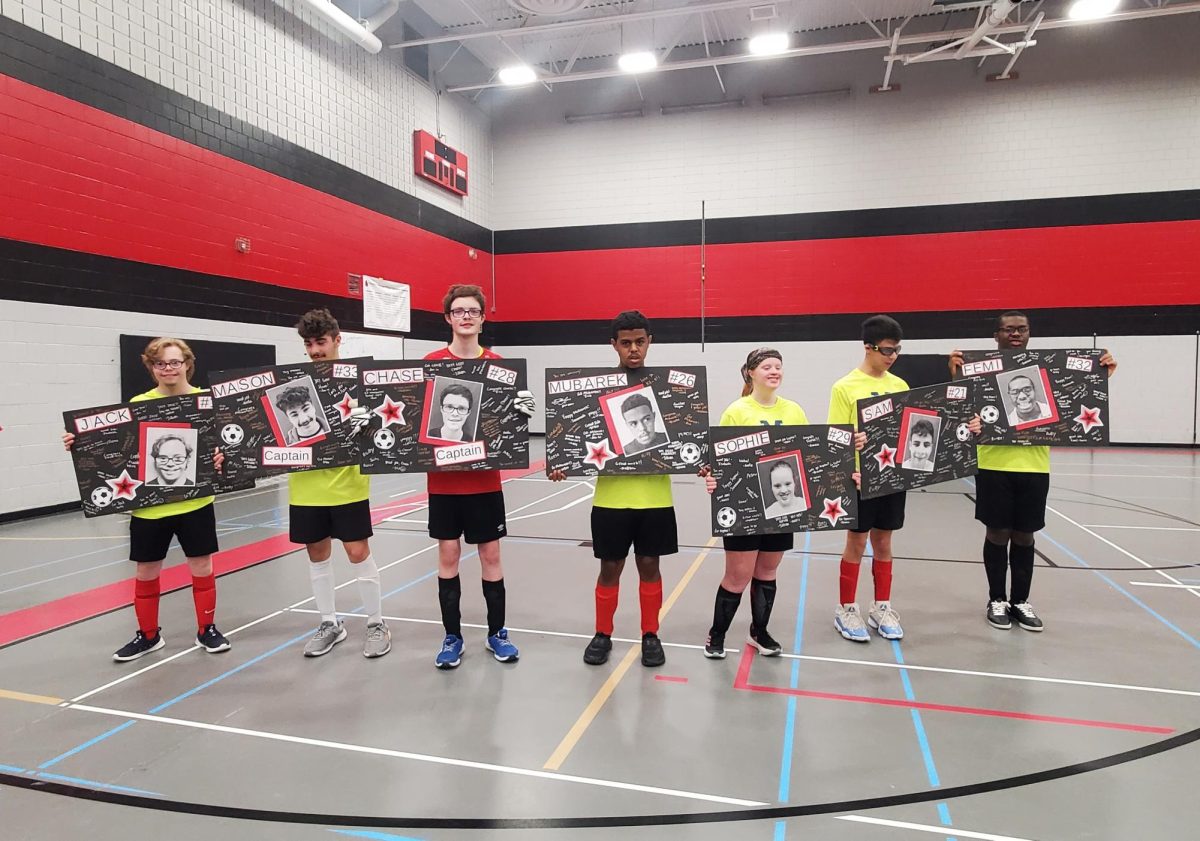 Seniors Jack Ridgeman, Mason Mora-Clark, Chase McCann, Mubarek Adem, Sophie Wynne, Sam Enright and Femi Alabi hold up their posters after their final soccer game on Oct. 29.