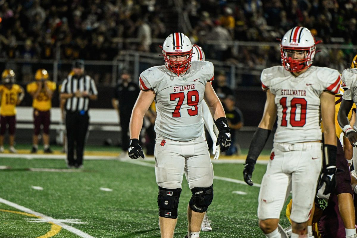 Andrew Olsen looks towards the sidelines during a football game. this shows Olsen in one of the two varsity sports he starts in.