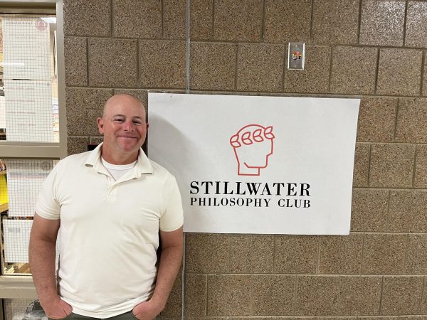 Social Studies teacher Mike Weiss stands in front of his room next to his Philosophy Club sign. He ponders the newest philosophical issues plaguing society.