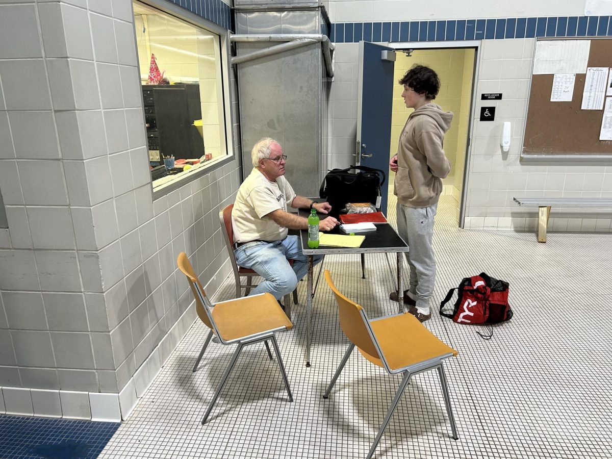 Coach Luke talks with a swimmer about their technique just before practice starts. He wants them to be ready for the conference meet coming up by improving their freestyle.