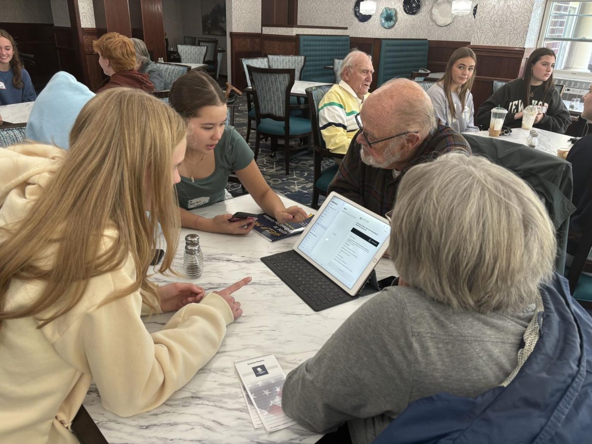 Two students from the Adopt a Grandparent program help residents at Boutwells Landing with technology. Although the program was originally aimed to help Boutwells residents with their technology, it has become more prominent in building meaningful relationships.