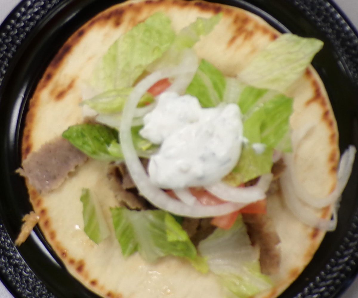 A gyro up close, showing its layers of meat, pita, and toppings. The textures and colors make it look as good as it tastes.
