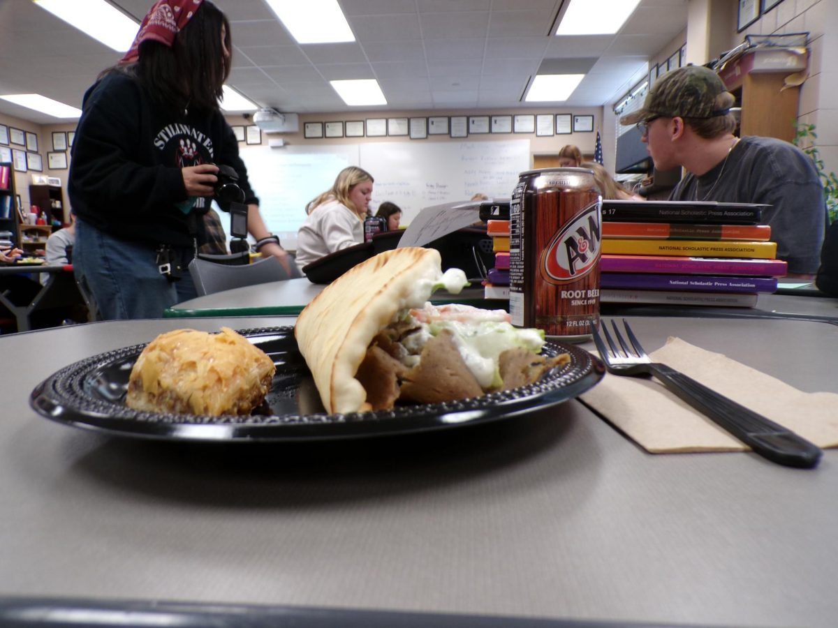 The gyro containing lamb, lettuce, and tomato rests next to the golden piece of baklava. The savory flavors mingle with the rich cinnamon sweetness.