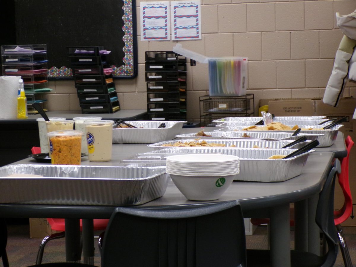 The full food setup before or during serving. Trays of pita, meat, sauces, and bowls are spread across the table.