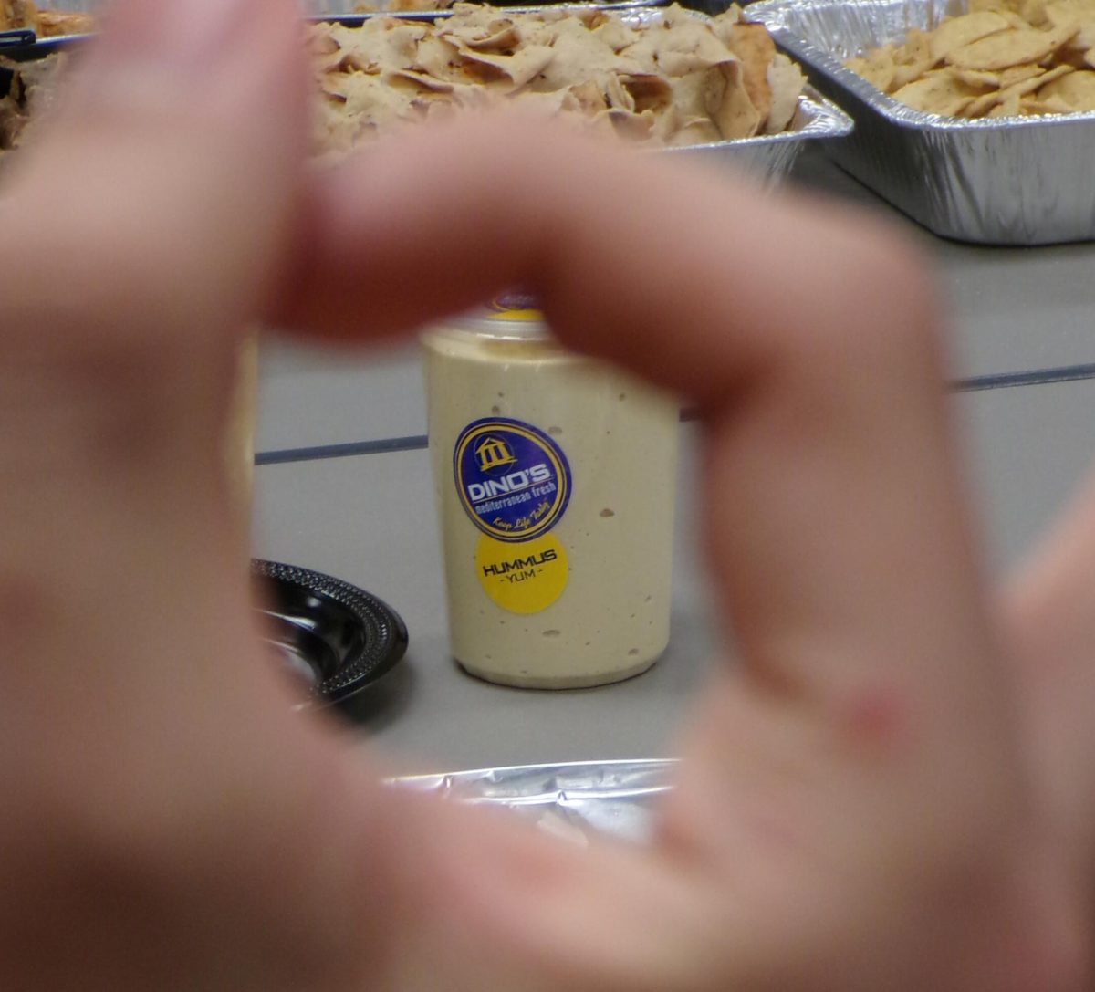 Hands form a frame around a tzatziki  sauce container, adding a emphasis to the condiment.