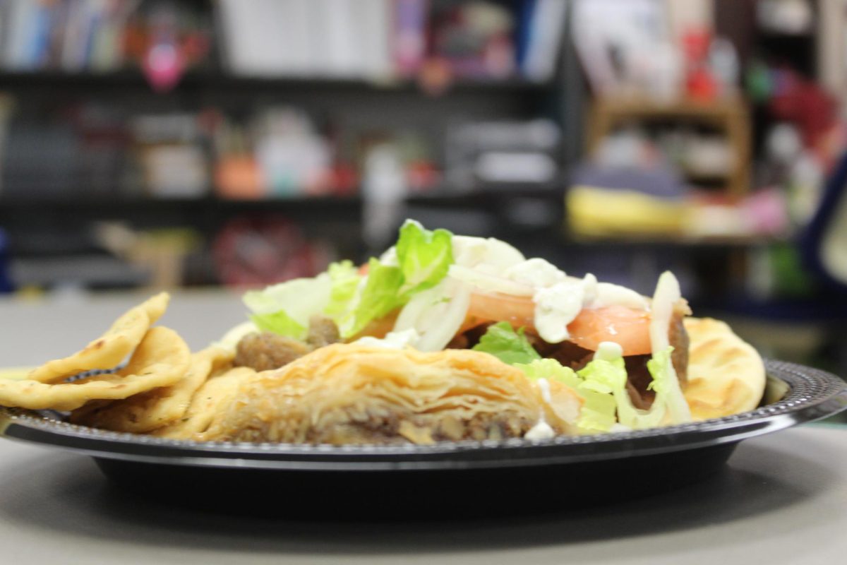 The gyro sits alone, with white sauce dripping from its peak. Atop the plate sits the baklava as well, a golden brown flaky desert.