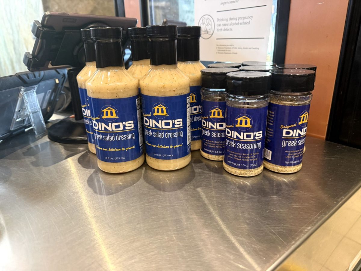 Taken at the silver counter of Dino's Gyros, their original Greek salad dressing and seasoning are laid out next to their policy paper for customer purchase. These complement the least to most ordered dishes there.