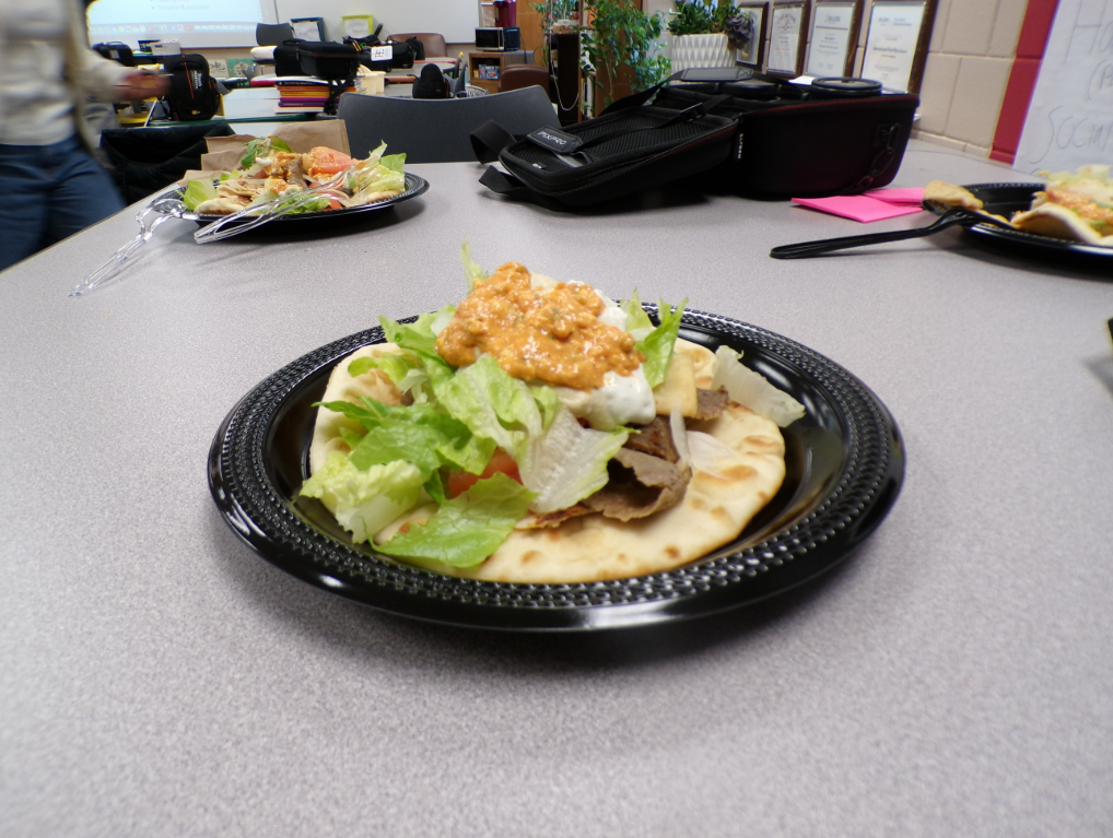A detailed view of a gyro showing its complexity: meat, vegetables, and sauces. The ingredients are of high quality and are well-combined.