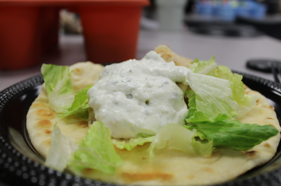 This is a photo of a tasty traditional gyro placed on a round black plate. The combination of the savory meat, juicy lettuce and the tangy Tzatziki sauce was phenomenal. 