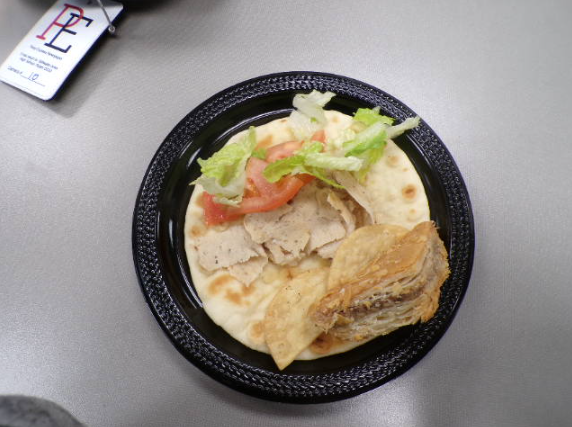 A single gyro with lettuce, tomato, and chicken on top of pita bread. The balance of flavors is maintained by the fresh preparation.