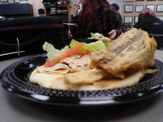 Baklava and a gyro plated with fresh vegetables and pita bread. The sweet baklava and intentionally flavored gyro exhibit freshness in every bite. 
