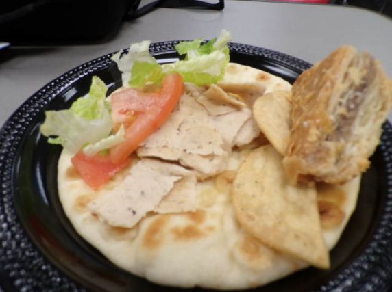 A wide shot of the assembled gyro with lettuce, tomato and chicken. The crafted meal is flavored carefully and made fresh.