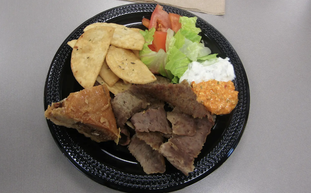 The gyro plate features seasoned lamb paired with creamy tzatziki and spicy feta dip.