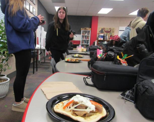 A group of students are trying Dino's Gyros. There is a collection of uniquely built meals.