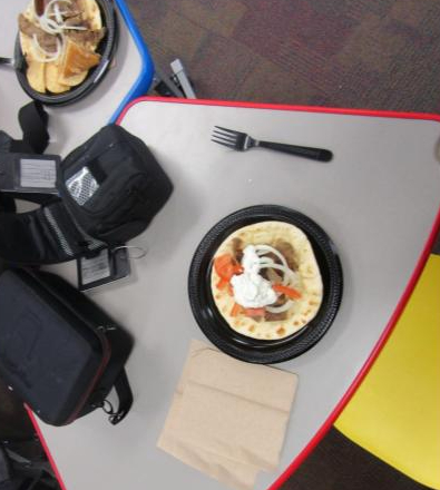The entirety of the gyro is captured. The large pita with Greek topping sprawled across the whole surface.