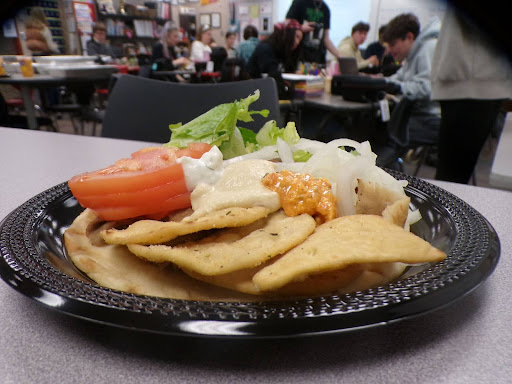 People could be seen enjoying their plate of food in the background. The plate pops from the background and you could see the seasoning on the chips.