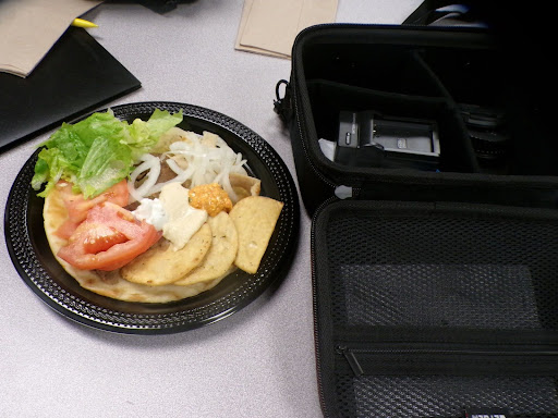 The colors of the plate, folder and camera case really matches well with the table color and napkins on it. The lively colors of the food makes it eye-catching from the objects around.