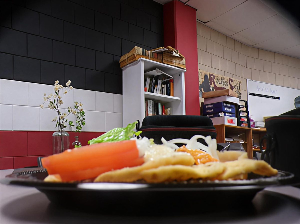 An unusual way to look at a plate of food but its comforting background kind of makes up for it. The stacked tomatoes and chips with the sauces, pile of onions and lettuce in the back makes the plate look like a feast for the eyes before the first bite.