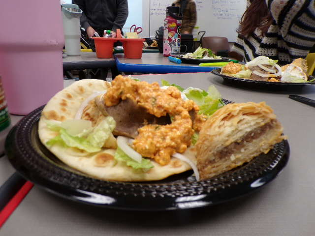 Gyro filled with meat, sauce, and vegetables. Sweet and delicious baklava right next to it.