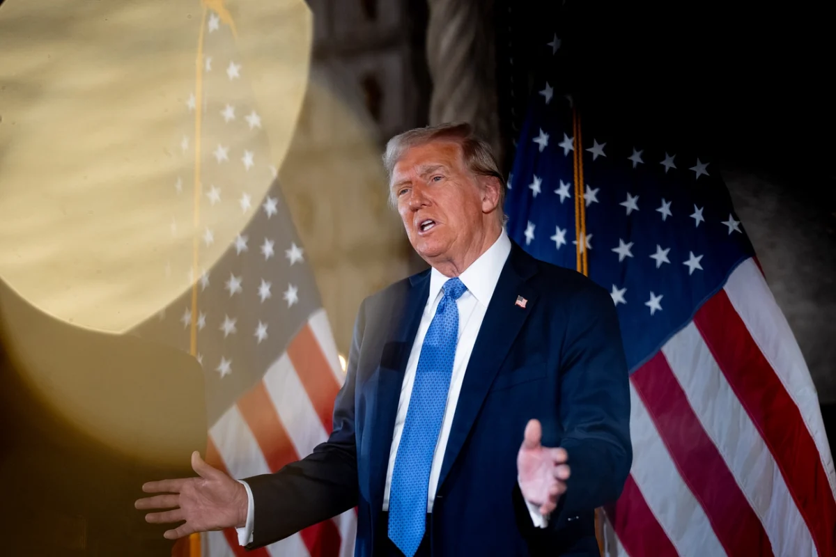 During a speech, Donald Trump spoke to an audience in the United States about political issues, addressing the public at an event while standing in front of American flags.