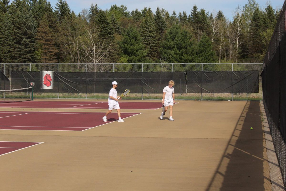 Two players track the ball from mid court, adjusting their positioning together. The point builds as they prepare for the next exchange.